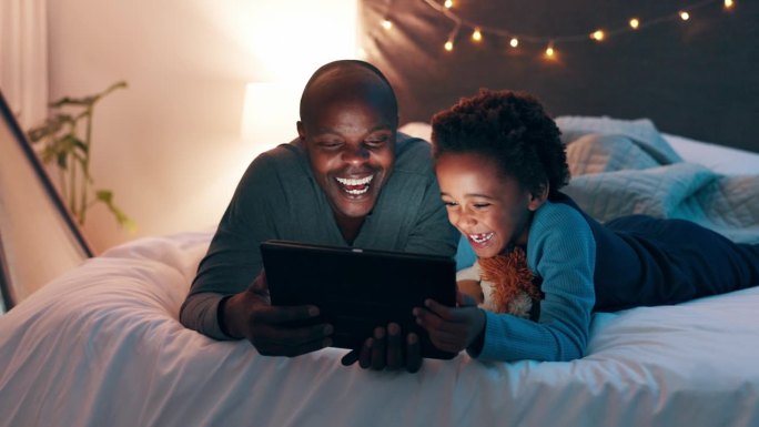 晚上，平板电脑和父子躺在床上看卡通、电影或在家看搞笑视频。数码，应用和黑人爸爸带着孩子在卧室里看网络