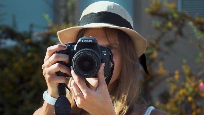 肖像女孩带着夏天的草帽拿着相机在一个阳光明媚的日子里拍照，慢动作
