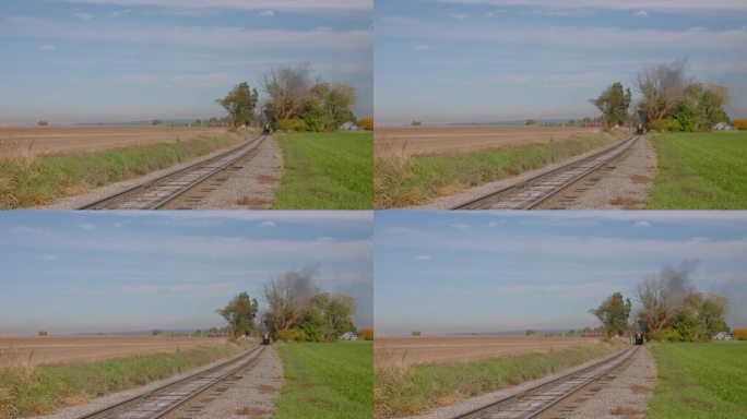 在一个阳光明媚的秋日，一列客运列车驶近，吹着烟雾和蒸汽的轨道侧视图