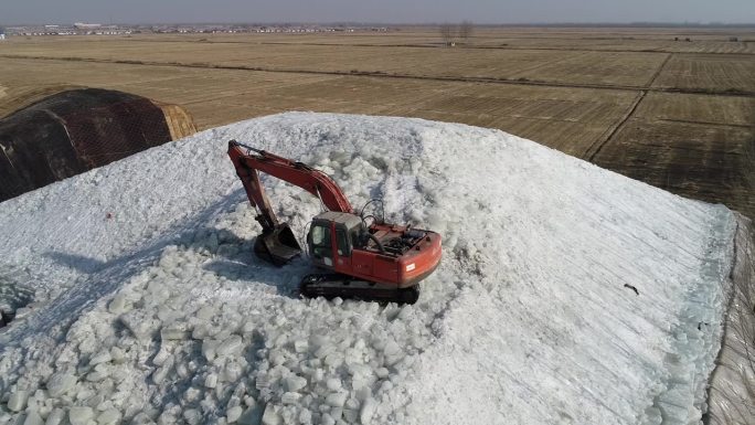 中国河北省滦南县——2021年1月22日:挖掘机在冰窖的冰垛上装冰。