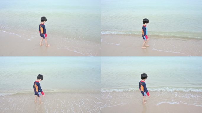 一个男孩走在沙滩上玩得开心，孩子戴着covid - 19口罩