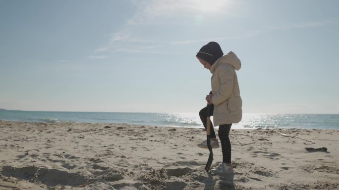 寒假期间，快乐的小女孩在沙滩上玩铲子