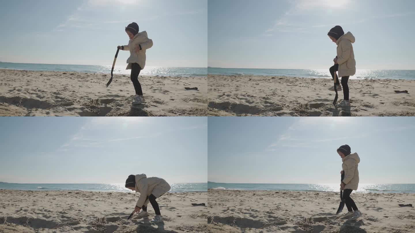 寒假期间，快乐的小女孩在沙滩上玩铲子