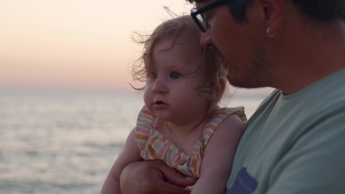 夏日夕阳下，一家人在海滩度假，父亲带着他的小女儿