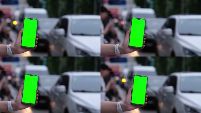 手展示绿屏的手机，汽车交通车流