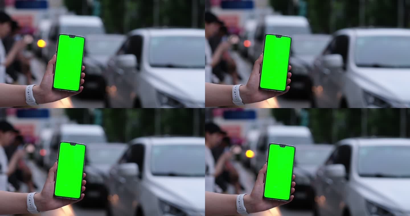手展示绿屏的手机，汽车交通车流