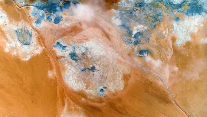 这张精彩的照片显示了活跃的地热喷口，在稳定的模式下，拍摄了蓝色的水和泥点，棕色的橙色地形和白色的硫磺