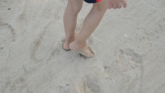 慢动作场景，特写赤脚小孩快乐地走在夏日海上旅行的沙滩上