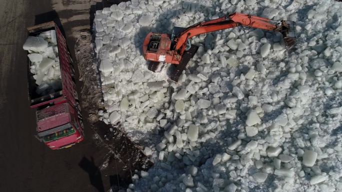 中国河北省滦南县——2021年1月22日:挖掘机在冰窖的冰垛上装冰。