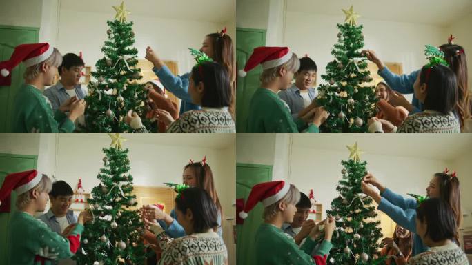 亚洲青年男女组团在家中装饰圣诞树，营造节日气氛