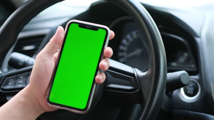 汽车里的驾驶员使用绿屏的手机
