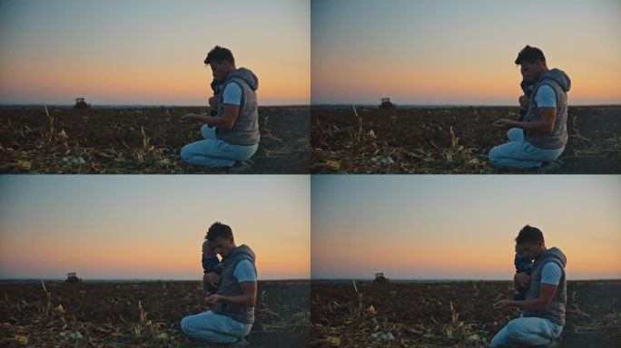 男农学家扛着儿子，在夕阳下对着天空分析田地里的土壤