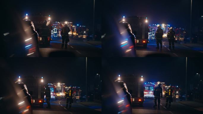 夜间，消防员在闪着蓝灯的消防车和道路上的交通附近一起工作