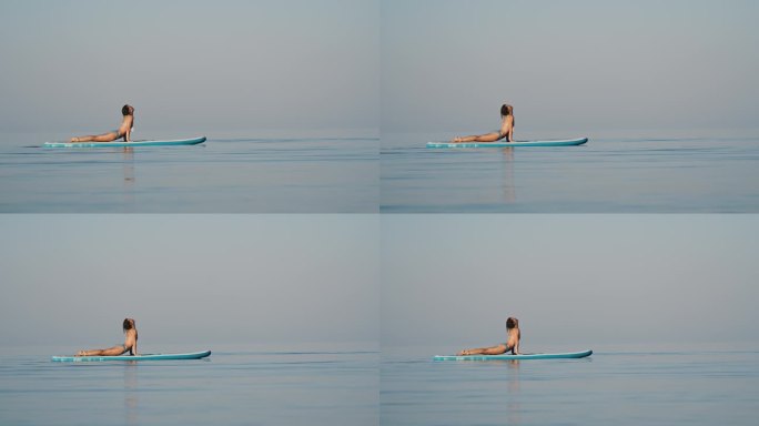柔韧的比基尼女子在海上冲浪板上练习瑜伽的慢镜头