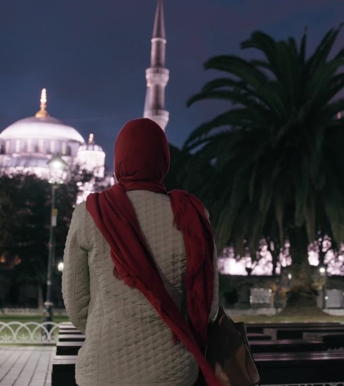 夜间祈祷:无法辨认的穆斯林妇女在灯火辉煌的广场上凝视着圣索菲亚大教堂的雄伟之美#圣索菲亚之夜#宁静的
