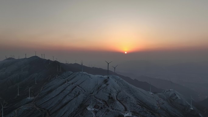 冬天日落下桂林高山上的积雪和风力发电风车