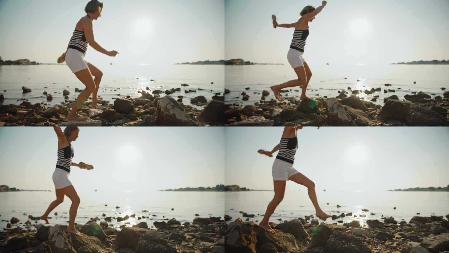 日落时分，一个无忧无虑的女人在海边的岩石上奔跑