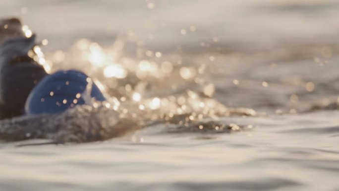 拍摄健康的女人与积极的生活方式游泳在日落的海洋在假期
