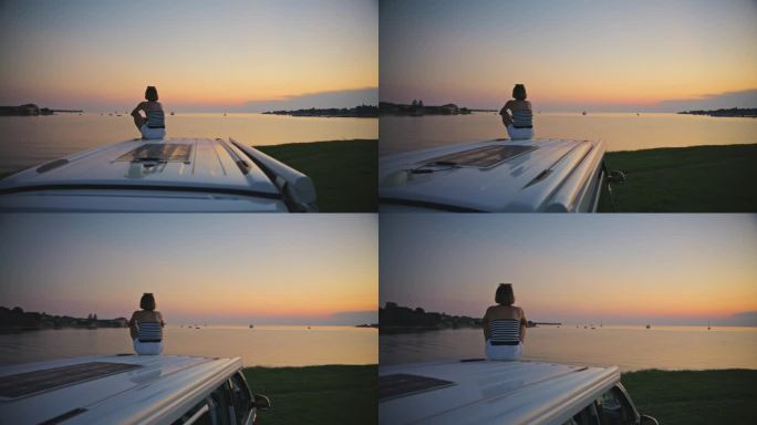 SLO镜头的女人坐在露营车的顶部，并在度假期间看日落的看法