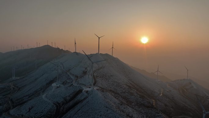 冬天日落下桂林高山上的积雪和风力发电风车