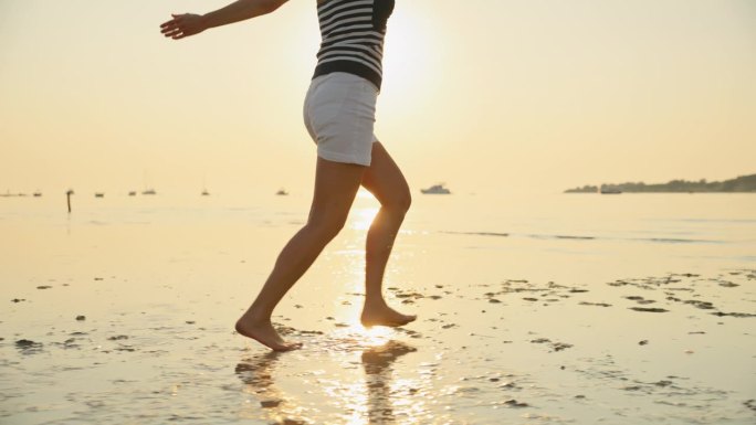 女子在沙滩上跑步，享受度假期间的日落