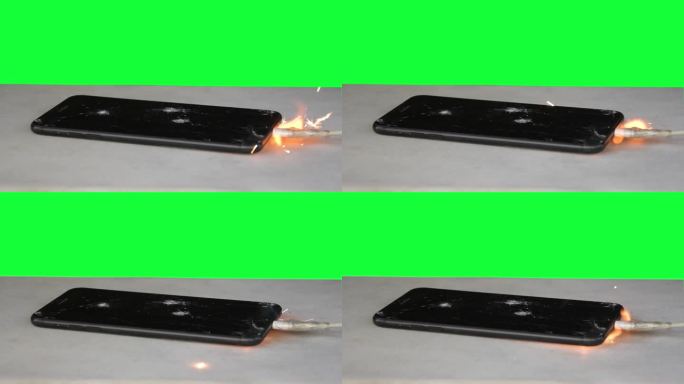 绿色背景下的智能手机因电池过热而点燃，火花和烟雾飞扬，变色。