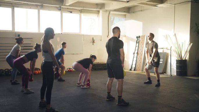 一群人在健身房用哑铃锻炼，在交叉教练的集体锻炼期间