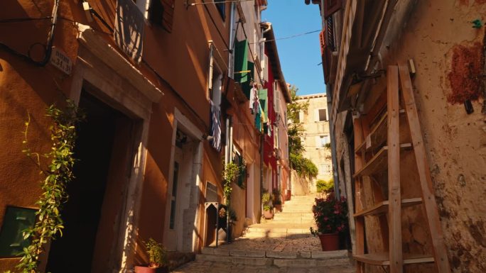 城镇老建筑中有台阶和盆栽的狭窄人行道的慢镜头镜头。罗维尼，伊斯特拉，克罗地亚。