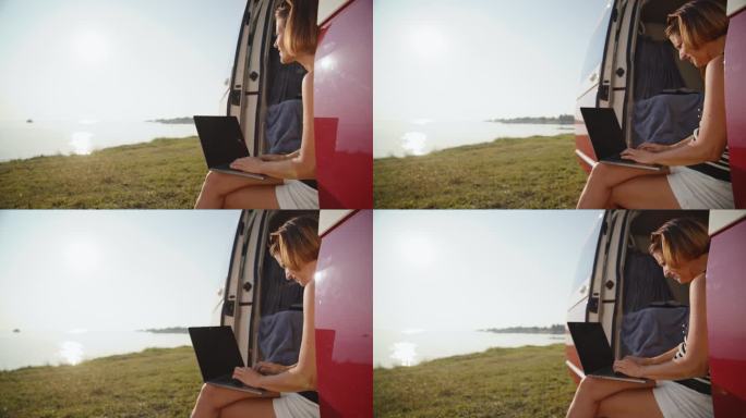 湖岸露营车里微笑的女自由职业者使用笔记本电脑的慢镜头
