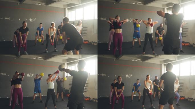 一群人在健身房用哑铃锻炼，在交叉教练的集体锻炼期间