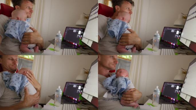 在家办公时，父亲抱着男婴使用台式电脑的锁定镜头
