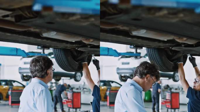 机械师和经理在修理厂修理汽车底盘