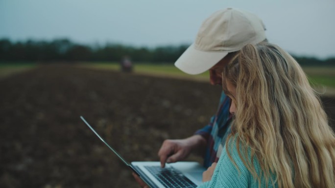 站在农田里用手提电脑工作的男女环保人士