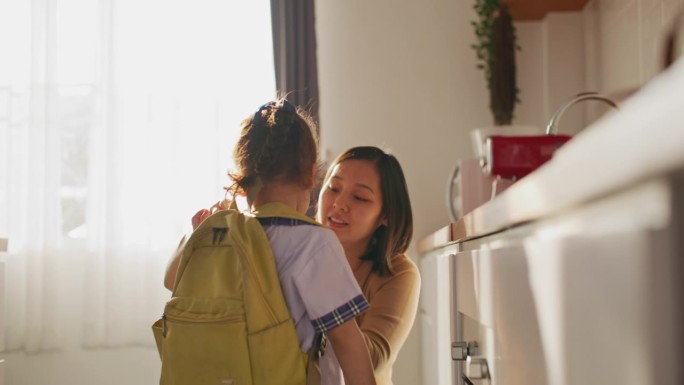 去学校前，妈妈正在家里帮女儿背书包