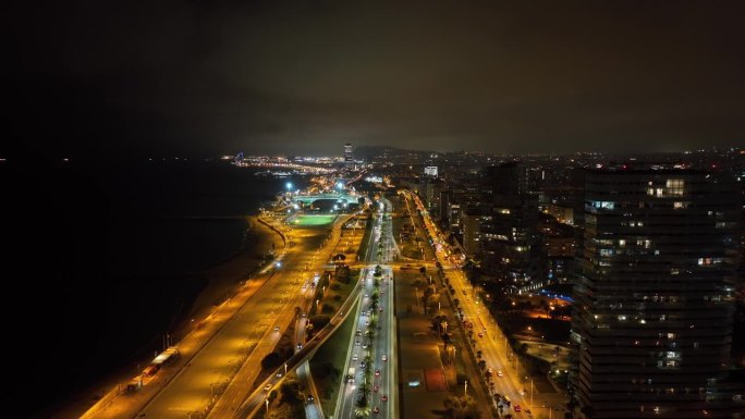 夜晚照亮巴塞罗那市著名的海滩湾交通街道道路航拍全景4k西班牙