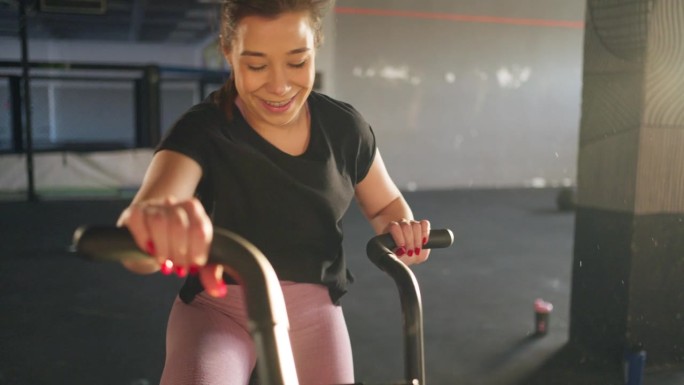 年轻的白人妇女在健身房的固定自行车机上锻炼