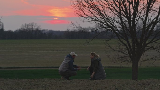 黄金时段，男女农民在田间检查土壤的SLO MO锁定镜头