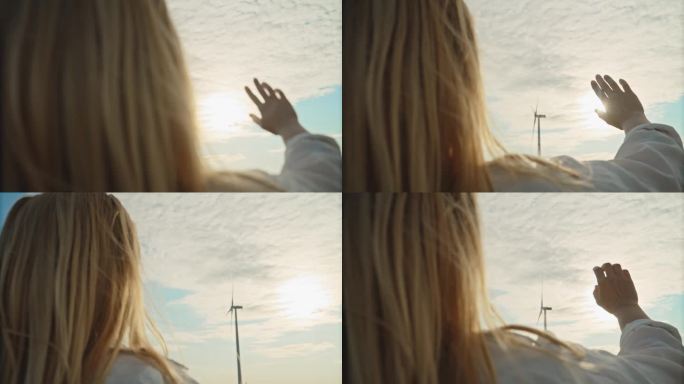 展望明天:一名女子向远处的风力涡轮机和灿烂的太阳伸出手