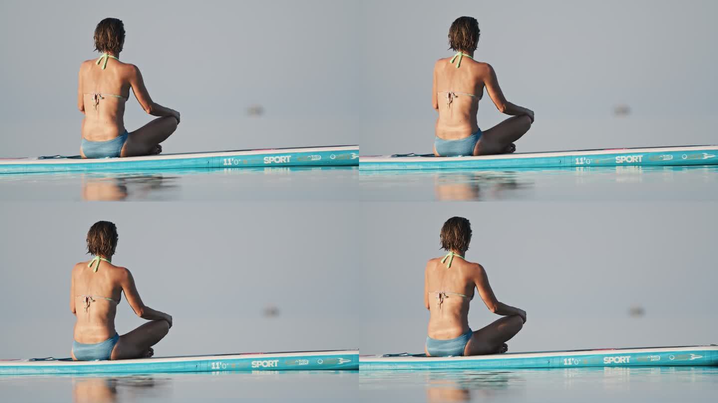 女子在海上冲浪板上进行放松练习的镜头