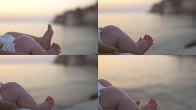 在日落的海边，顽皮的幼儿悬挂着双腿的特写镜头