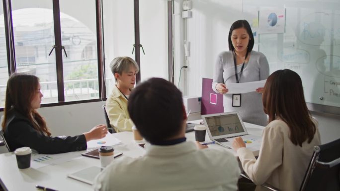 怀孕的女商人在现代办公室里与同事们围坐在桌子旁开报告会