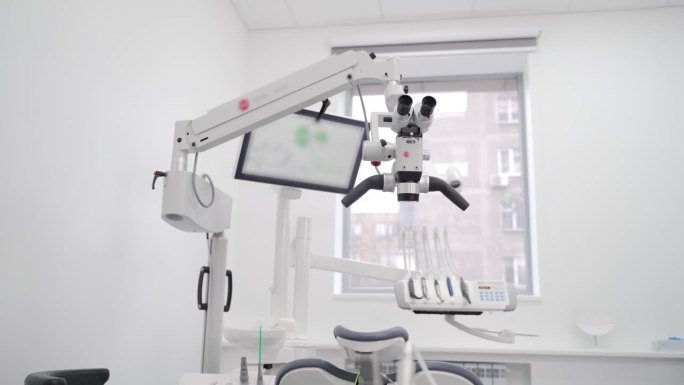 现代牙科诊所旋转式双筒显微镜。使用牙镜治疗患者牙齿。牙科诊所专业设备。牙齿显微外科和修复术。
