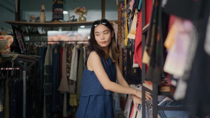 亚洲年轻女性在购物中心选购服装。