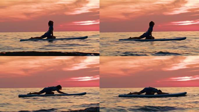 女子在冲浪板上练习瑜伽在海上对天空日落时的慢镜头