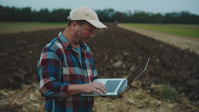男农艺师在农田工作时使用笔记本电脑