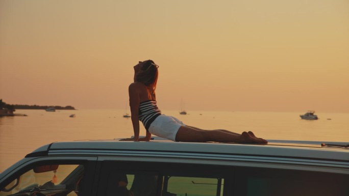 日落时分在海边露营车上锻炼的女子的慢镜头镜头