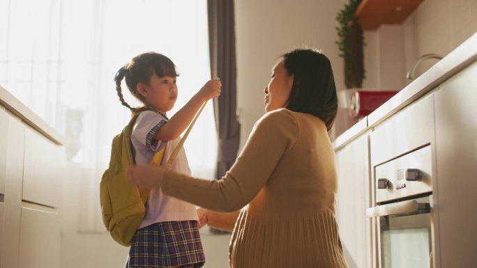 去学校前，妈妈正在家里帮女儿背书包