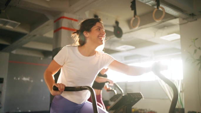女运动员，在健身房的固定自行车机上一起锻炼
