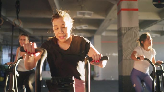 白人女运动员，在健身房的固定自行车机上一起锻炼