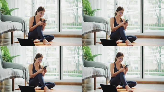一名女子在家训练后坐在窗台上玩智能手机